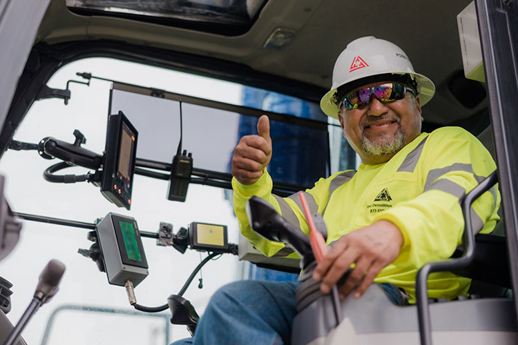 FOSS worker in hard hat and safety vest giving thumbs up